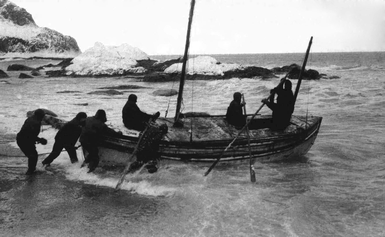 Fotografía de 1916 de hombres empujando un bote salvavidas al agua desde una playa rocosa en la isla Elefante